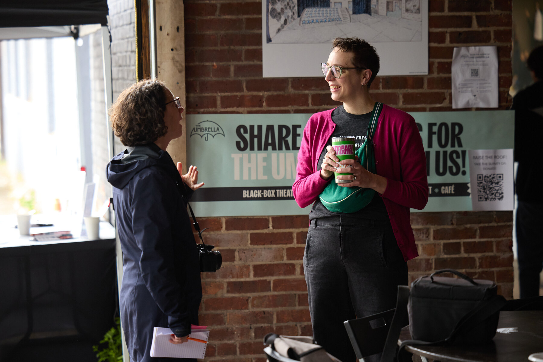 A Broken Umbrella ensemble members talking with visitors during Bagels in the Black Box